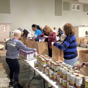 Volunteers operate an assembly line packing bags of food for local seniors.